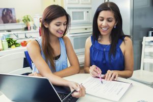 Mother helping daughter fill out College Applications in the Kitchen