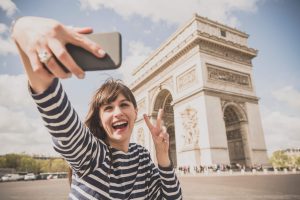 Young woman taking selfie by Arc de Triomphe